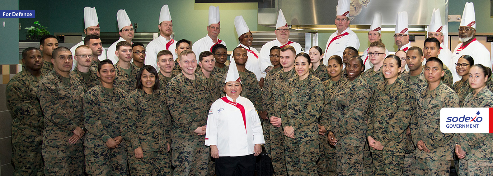 Group of male and female soldiers and sodexo military chefs posing together for a group photo
