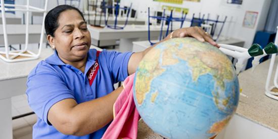 A Sodexo employee cleaning a globe in a school classroom