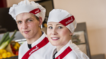 a male and female chef in sodexo uniform smiling at the camera
