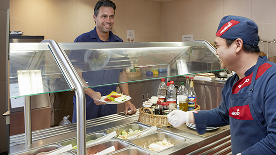 A sodexo employee serving food in a lunch room