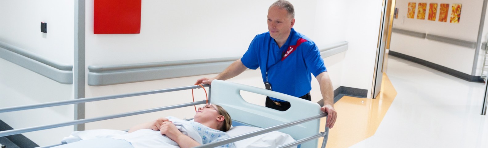 A man gently pushing a woman in a hospital bed