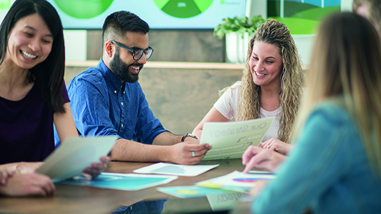 Co-workers looking at sheets of paper together and smiling