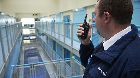 A male prison officer talking in to a walkie talkie