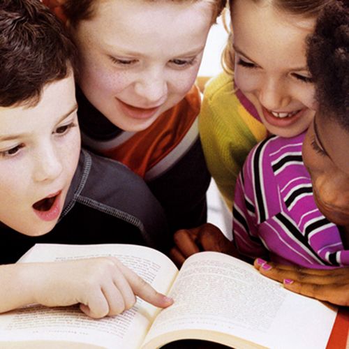 four children reading a book together